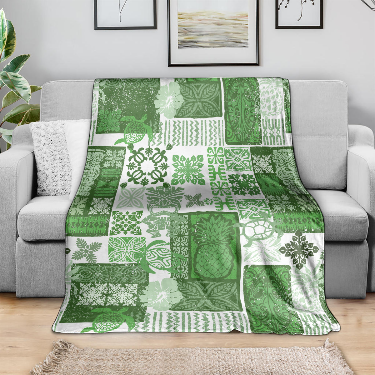 Green and white quilt blanket with tropical patchwork motifs, draped over a sofa.