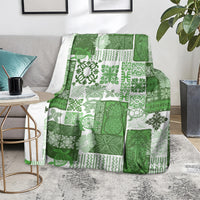 Green and white quilt blanket with tropical patchwork design, laid over a chair.