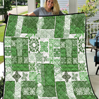 Green and white tiki patchwork quilt with tropical floral motifs and black binding edge