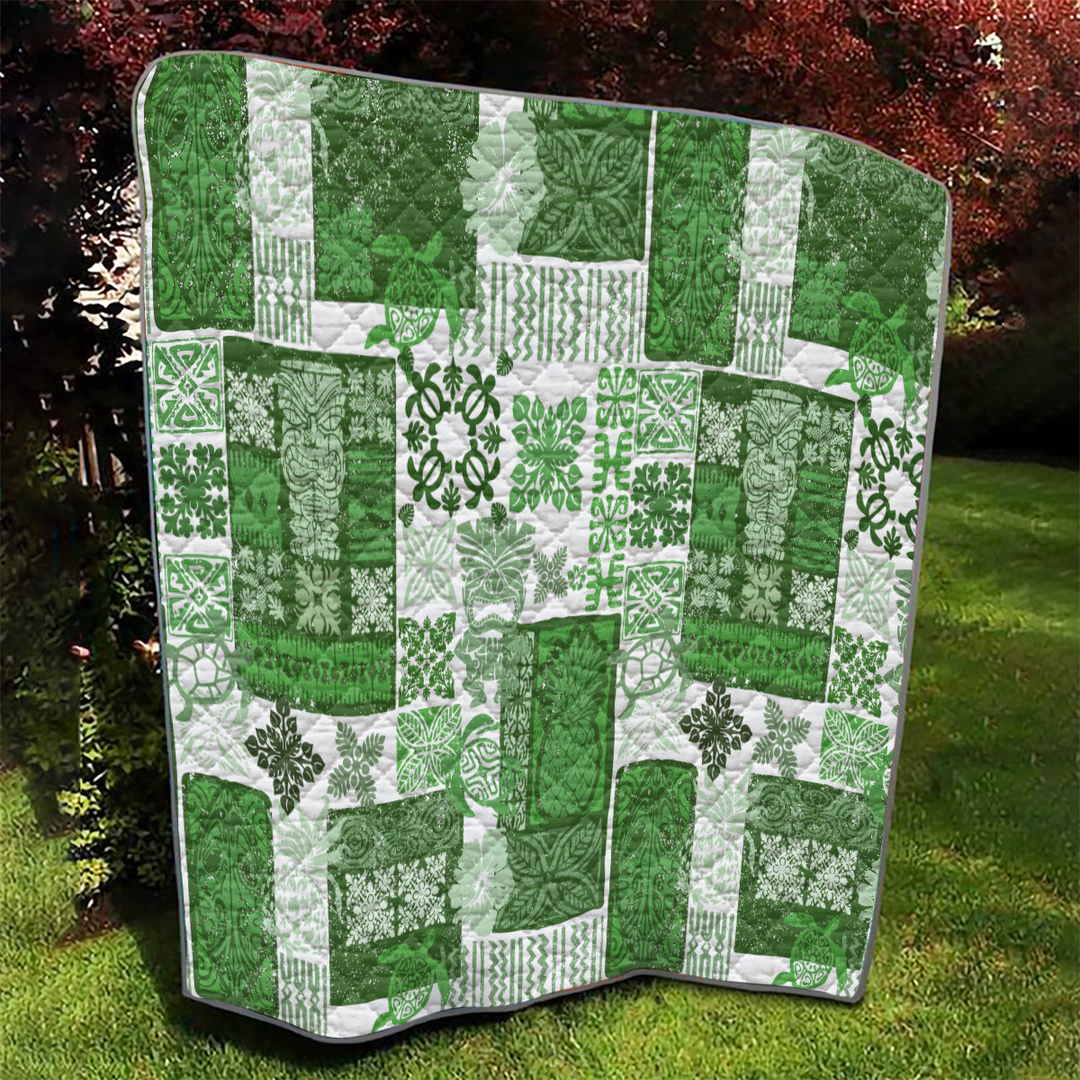 Green and white tiki patchwork quilt with tropical floral motifs and black binding edge view