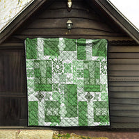 Green and white tiki patchwork quilt with tropical floral motifs and black-framed hanging view