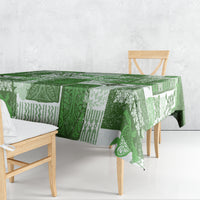 Green tiki patchwork tablecloth with patterned panels, draped over a dining bench table
