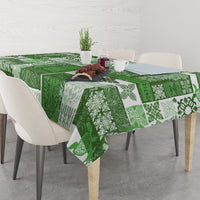 Green patchwork tiki tablecloth with floral and geometric designs on a dining table