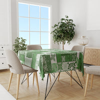 Green tiki patchwork tablecloth with mixed motifs on a dining table with chairs