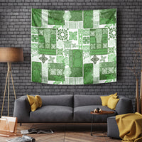 Green tropical tapestry featuring block patchwork tiki faces, plants, and motifs