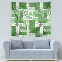 Green tropical patchwork tapestry with repeating tiki faces, leaves, and ornament blocks