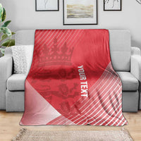 Red cricket blanket on a gray sofa, crown motif, diagonal stripes, and vertical 'YOUR TEXT'