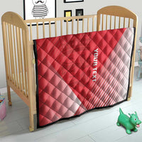 Red and white diagonal quilt blanket with diamond quilting and black border on a crib