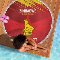 Red round beach blanket with white fringe, Zimbabwe text and yellow bird graphic.