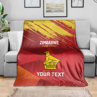 Zimbabwe cricket blanket draped on sofa, red with yellow emblem and “YOUR TEXT” print