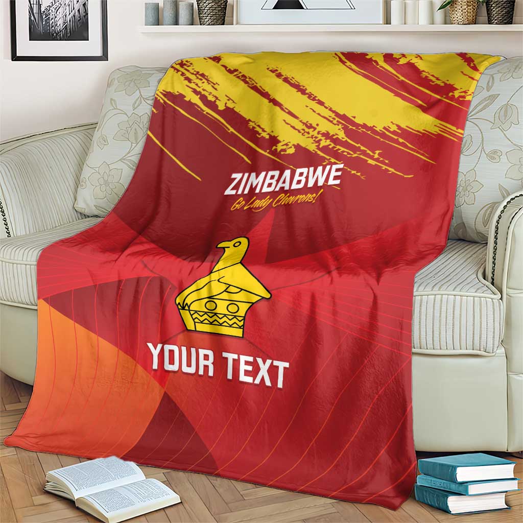 Zimbabwe cricket blanket on couch, red and orange pattern with yellow emblem and “YOUR TEXT”