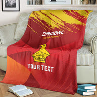 Zimbabwe cricket blanket on couch, red and orange pattern with yellow emblem and “YOUR TEXT”