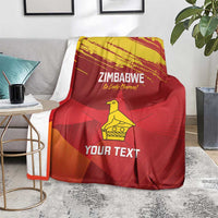Zimbabwe cricket blanket on floor, red with yellow emblem and “YOUR TEXT” lettering