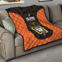 Orange and black quilt draped on sofa with Colombia logo and diamond stitched panels