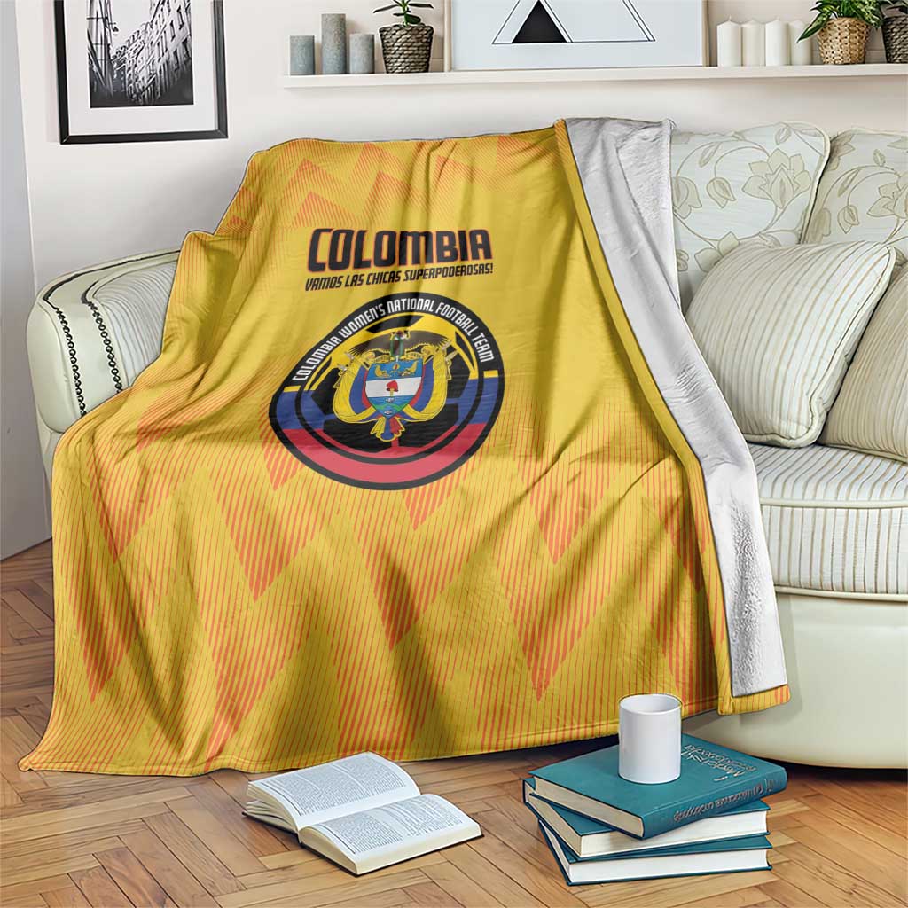 Yellow Colombia football blanket with crest and zigzag pattern, laid across a bed