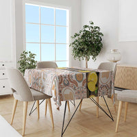 Tablecloth draped over dining table, cream background with Sicilian mosaic pattern in tan and blue