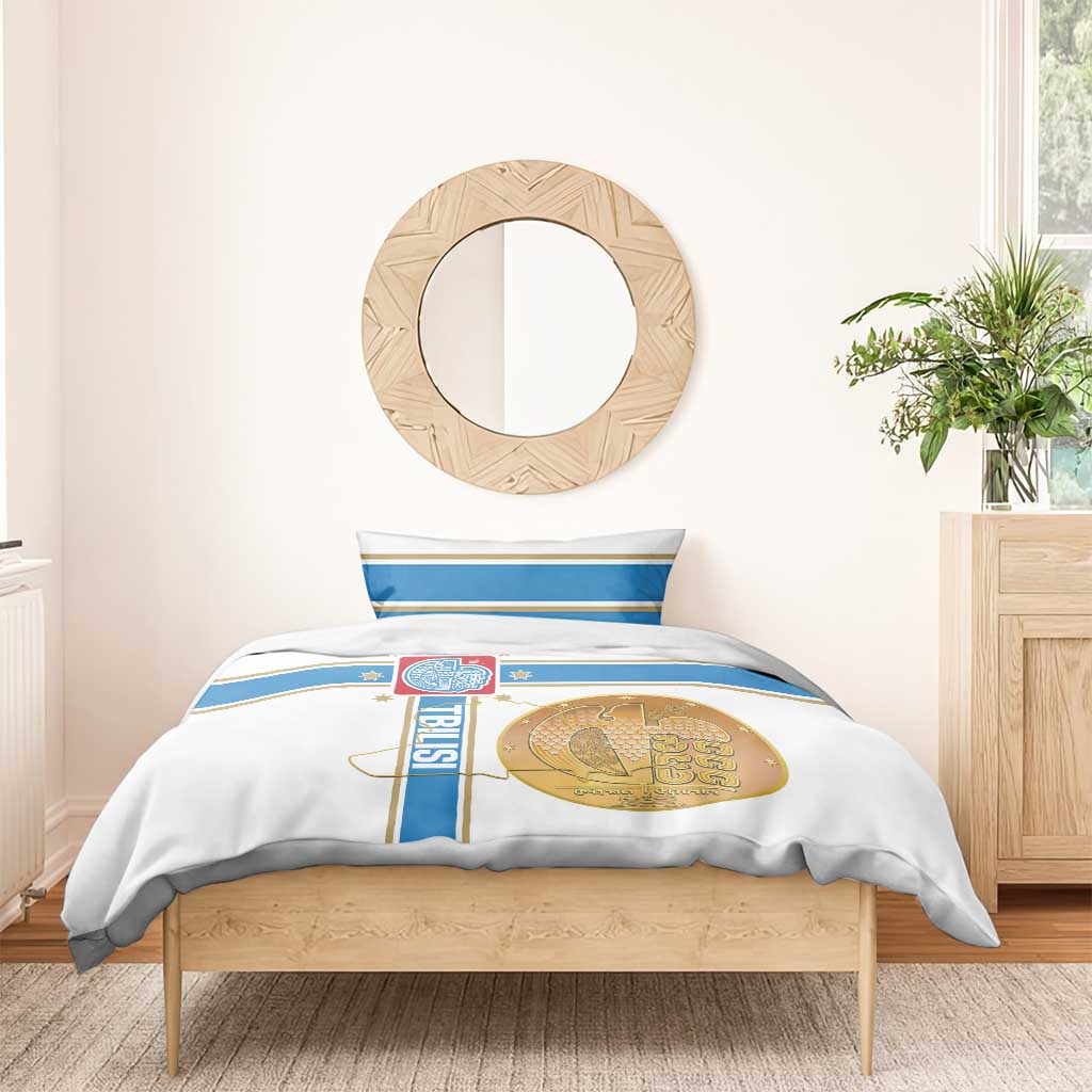 White duvet and pillow set with blue stripes and gold circular emblem, for a bed