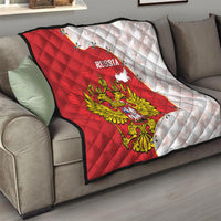 Folded red and white Russia quilt on sofa with quilted pattern and eagle crest