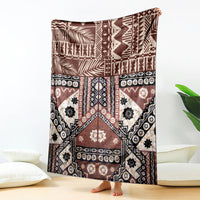 Brown geometric tapa-pattern blanket with black accents and white motifs, draped