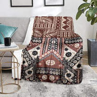 Brown tapa-pattern blanket folded over sofa seat, black and white motifs