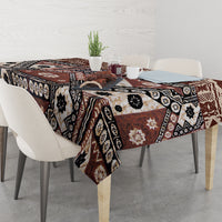 Brown patterned tablecloth with black, cream, and rust geometric and floral blocks.