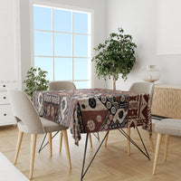 Brown masi tapa tablecloth with geometric and floral pattern across the tabletop.