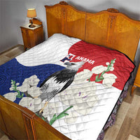 Quilt blanket on bed, white base with red top, blue bottom; harpy eagle and flowers