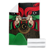 Libya flag-style blanket close-up showing hands holding 'LIBYA' emblem on black-red-green