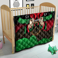 Libya flag-style quilt on crib with red, black, green design and hands emblem.