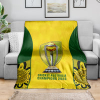 Cricket blanket spread on sofa: yellow center, dark green sides, trophy and Champions 2023