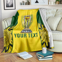 Yellow and green cricket blanket on a couch with trophy emblem and 'YOUR TEXT' wording