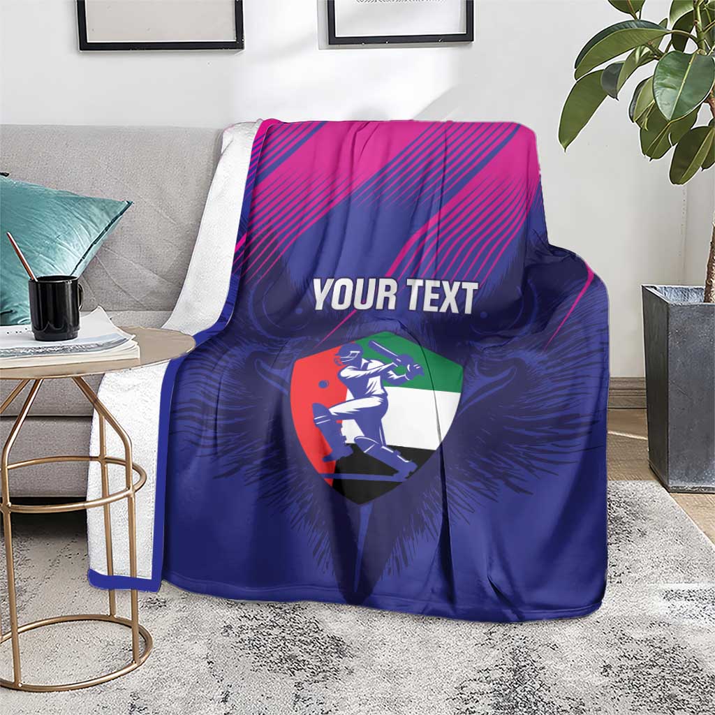 Cricket blanket draped over sofa: blue with magenta stripes, 'YOUR TEXT' and UAE shield