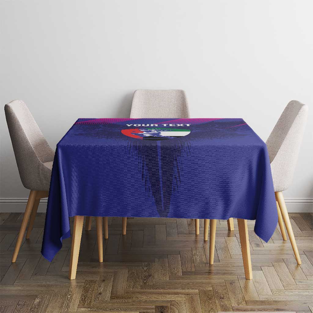 Blue tablecloth featuring crest graphic and “YOUR TEXT” on table with four chairs