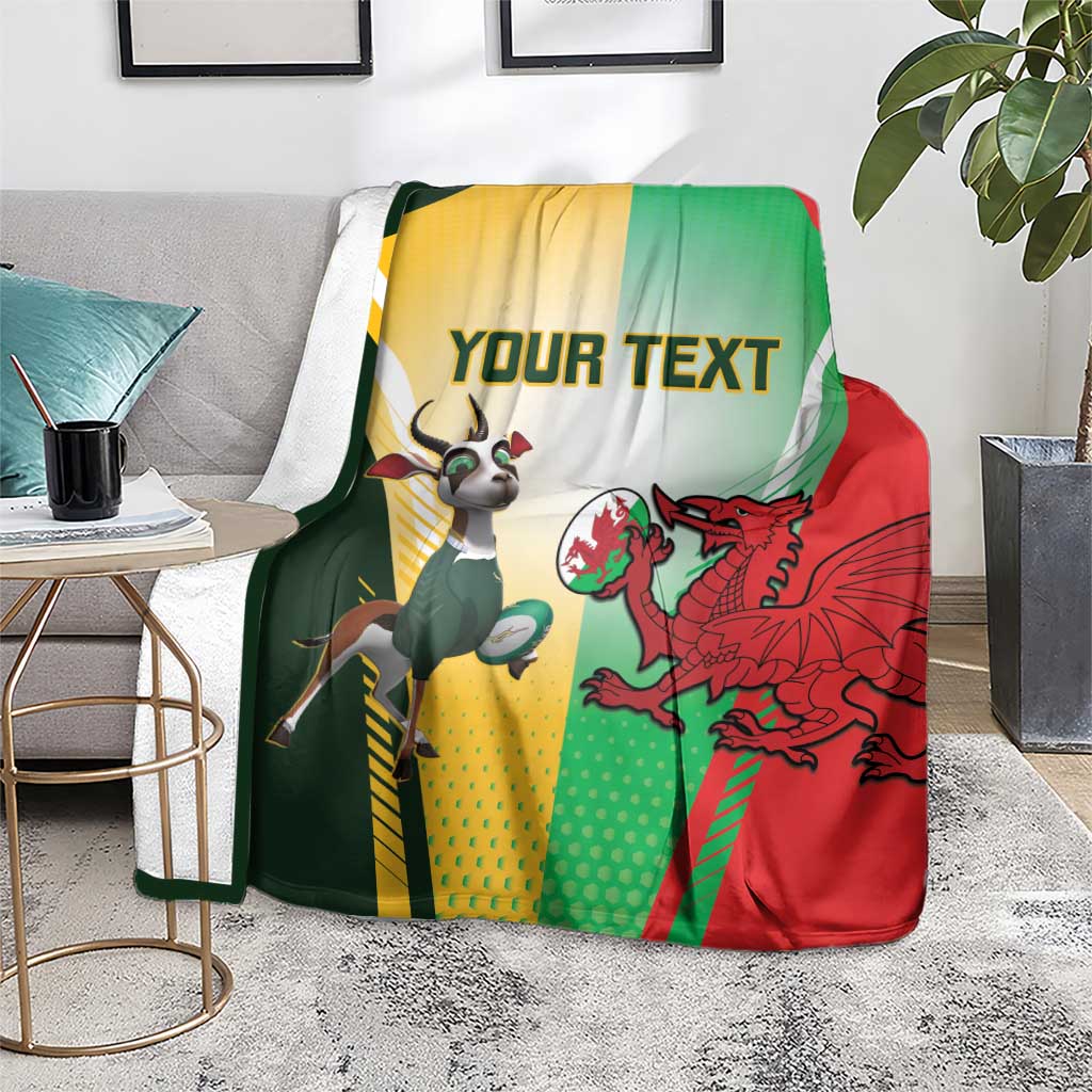Rugby blanket on light rug with green, red, yellow flag design, dragon and goat mascots