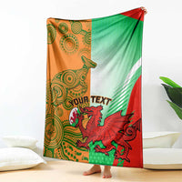 Rugby blanket draped on a couch in green, red, and orange with mascot crest and patterns.