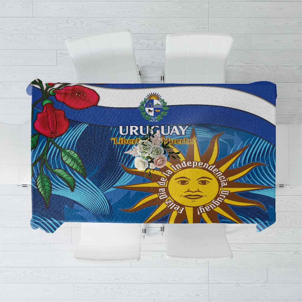 Folded blue tablecloth showing Uruguay crest, sun face, and ceibo flower artwork