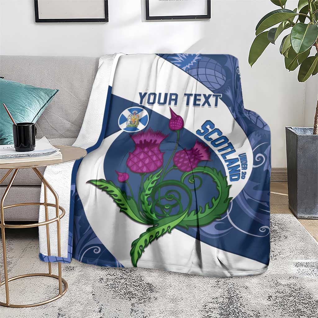 Blue and white rugby blanket draped over sofa with thistle floral and Scotland word