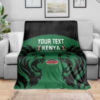 Green Kenya rugby blanket with black border and lion graphic, spread on gray couch