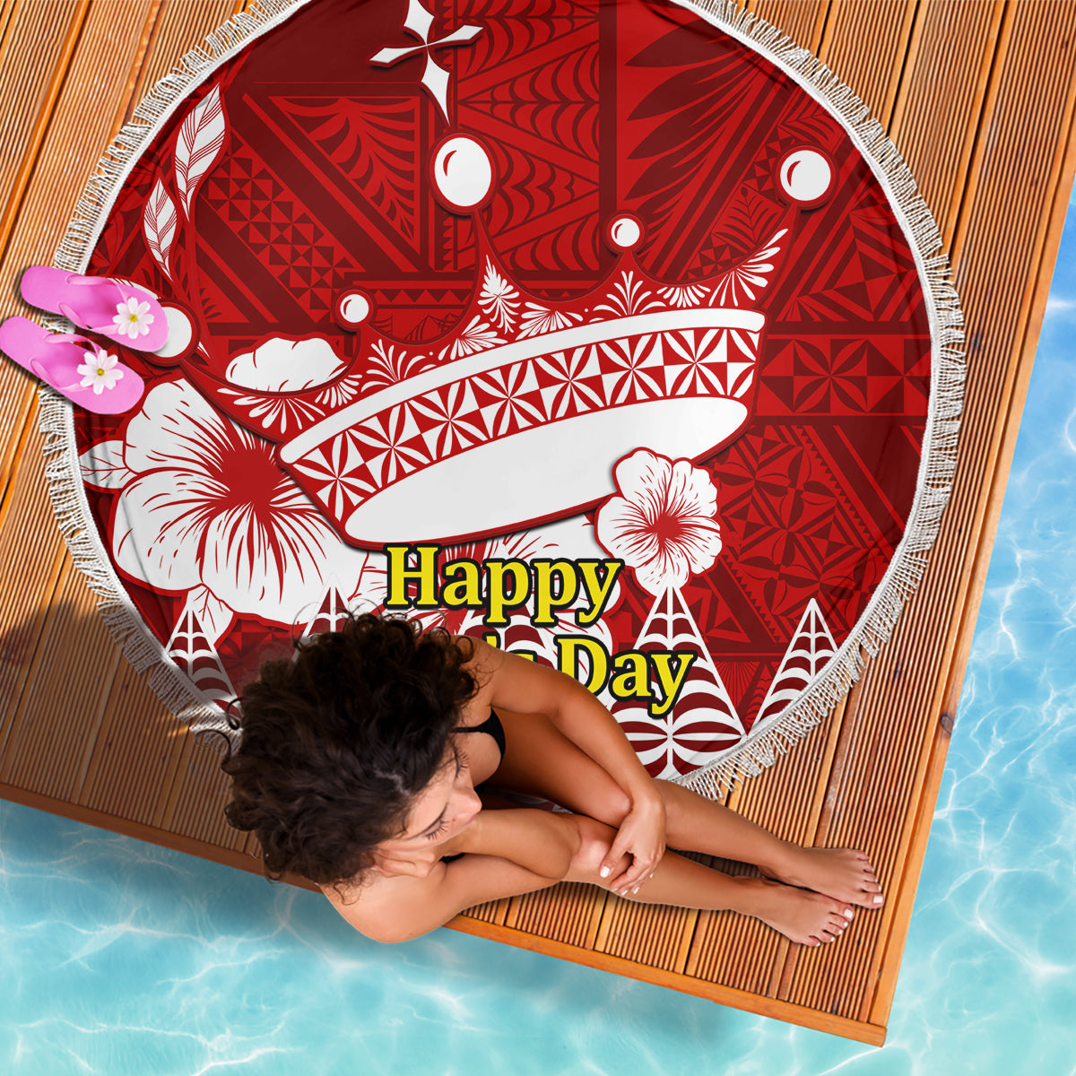 Red round beach blanket with white patterns and tassel fringe, laid flat at an angle