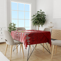 Red tablecloth with white patterned border, laid across dining table with chairs