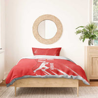 Red cricket duvet with player illustration and YOUR TEXT; two pillowcases on a bed frame.