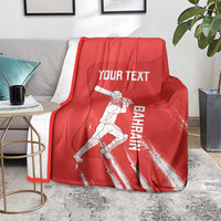 Red cricket blanket with Bahrain player graphic and Your Text print, draped on gray couch