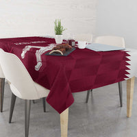 Maroon tablecloth with white Qatar cricket player print and jagged edge, on dining table.