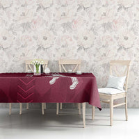 Maroon Qatar cricket tablecloth with white design on table, with chairs against floral wall.
