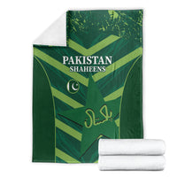 Green Pakistan Shaheens blanket with stacked white towels, logo and lettering visible
