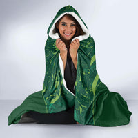 Green hooded blanket with hood up and gray sherpa lining, laid over lap