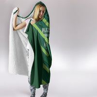 Green hooded blanket worn as a cape with hood; gray sherpa lining visible