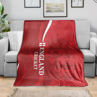 Red England cricket blanket with white “ENGLAND CRICKET” text and lion crown emblem, laid on sofa
