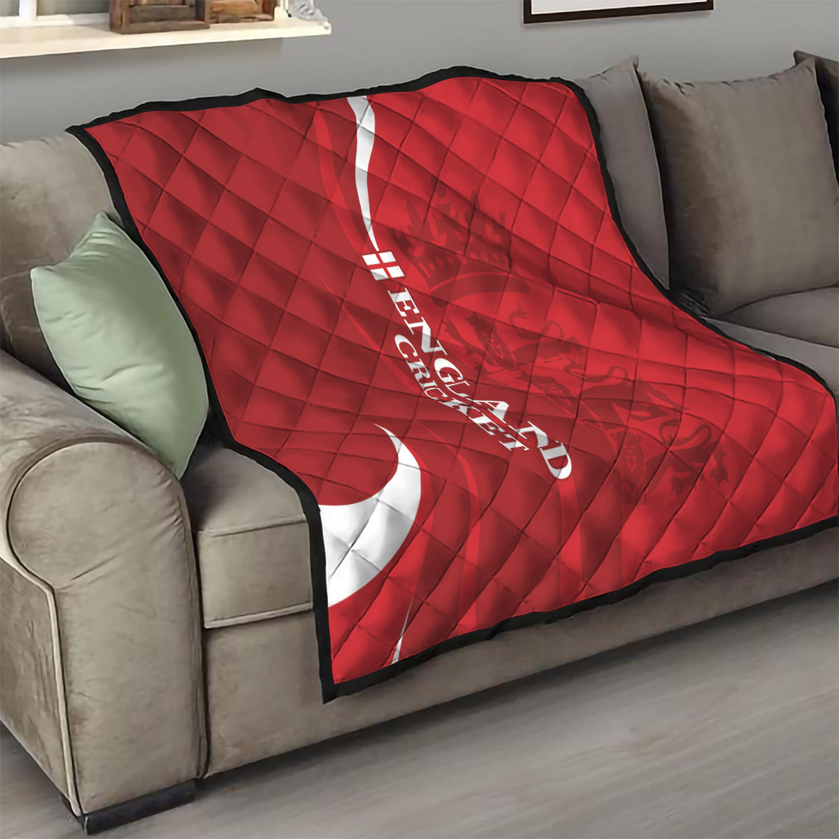 Red England cricket quilt folded on sofa with white crescent and vertical text