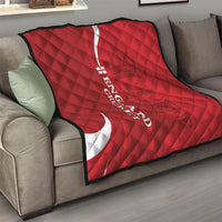 Red England cricket quilt folded on sofa with white crescent and vertical text